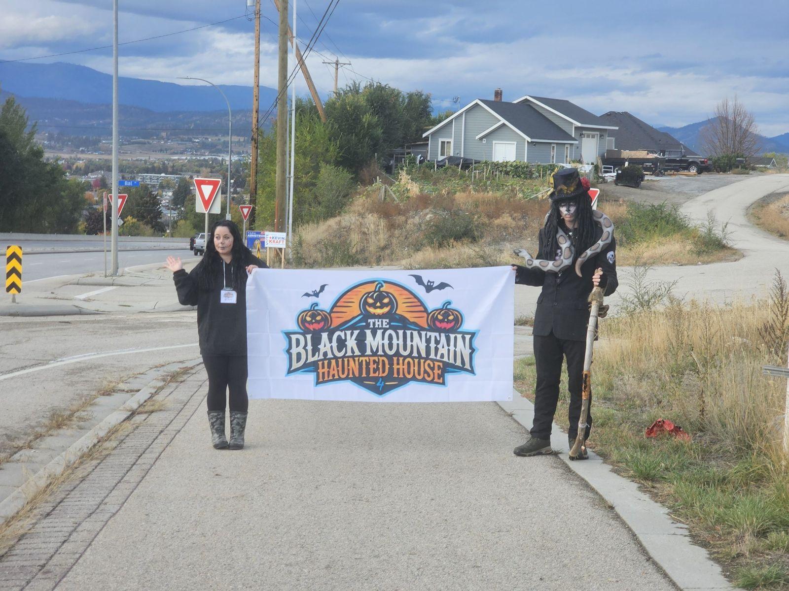 Volunteers holding the Black Mountain Haunted House banner above the Okanagan valley