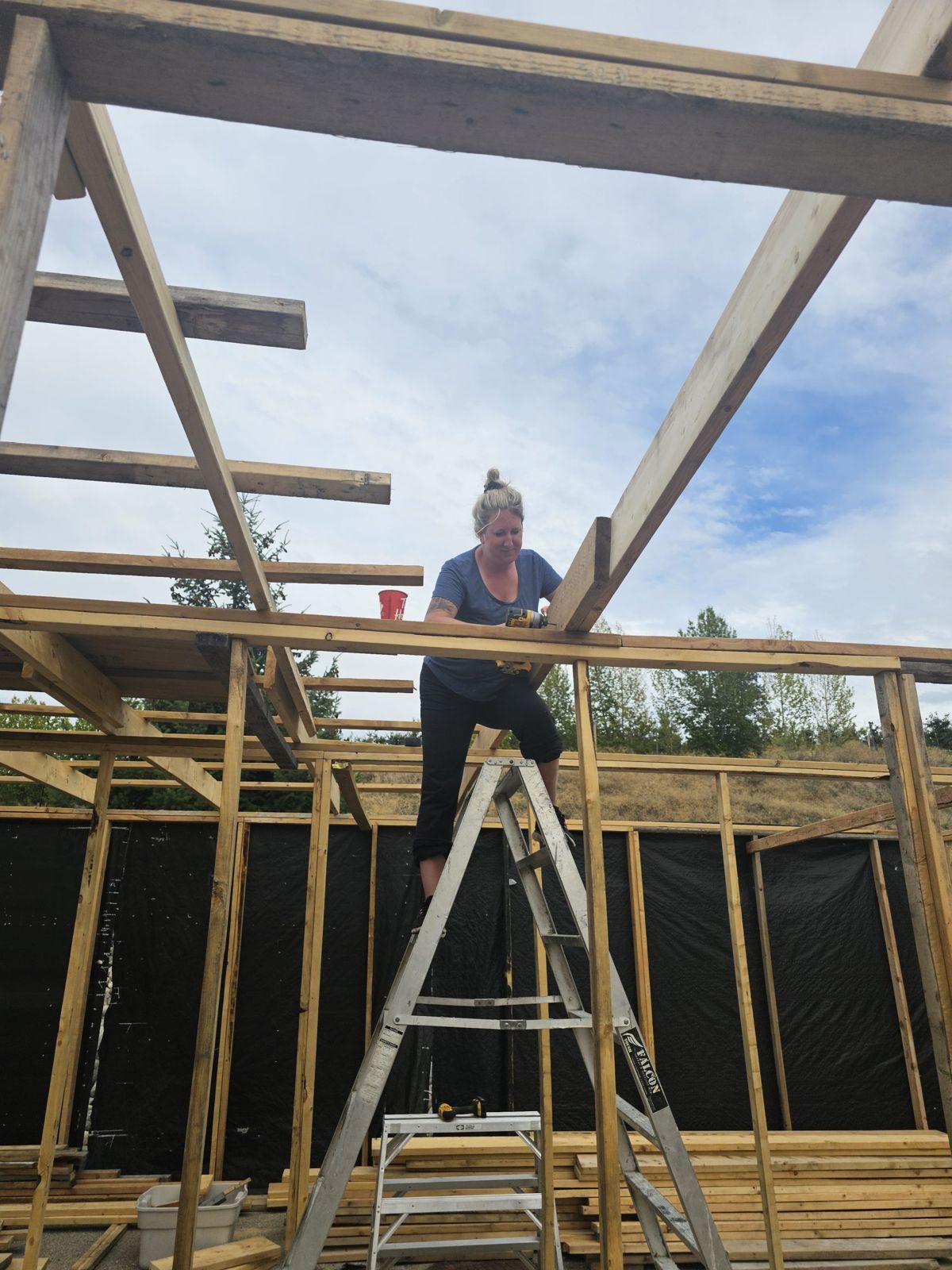 A volunteer working on the framing from a ladder