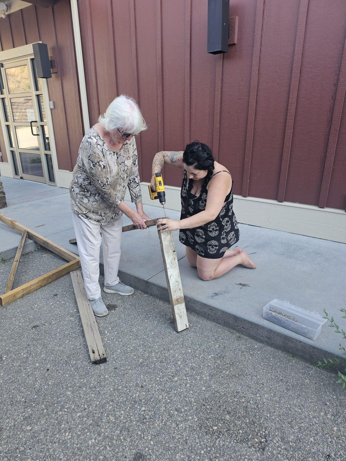 Two volunteers sawing lumber together